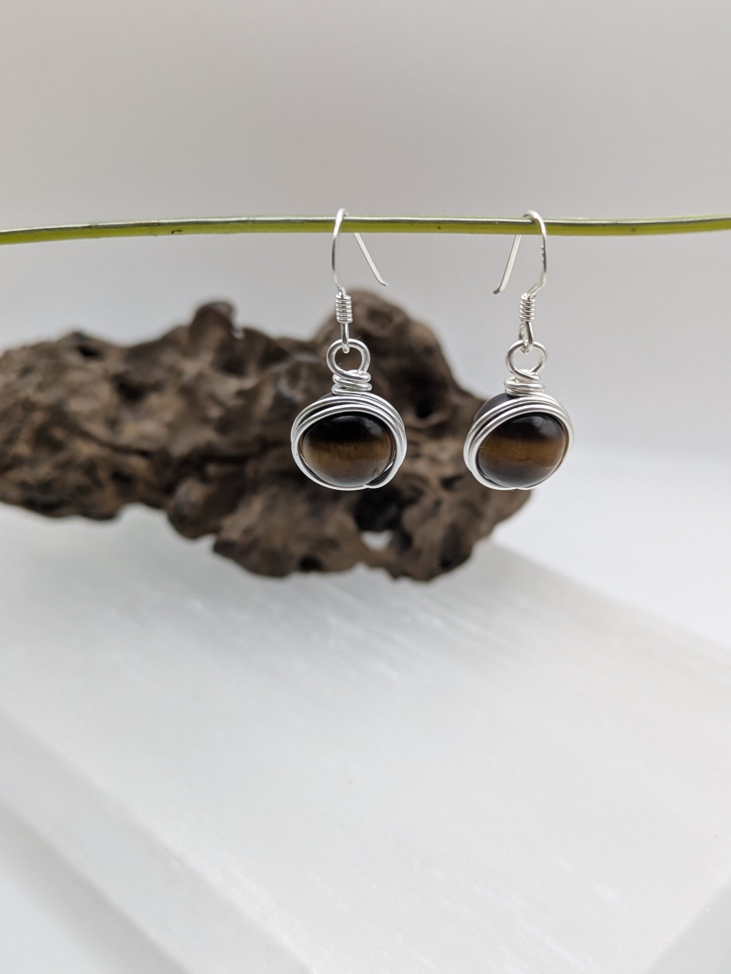 Silver earrings featuring round Tiger’s Eye gemstones with golden-brown chatoyancy.