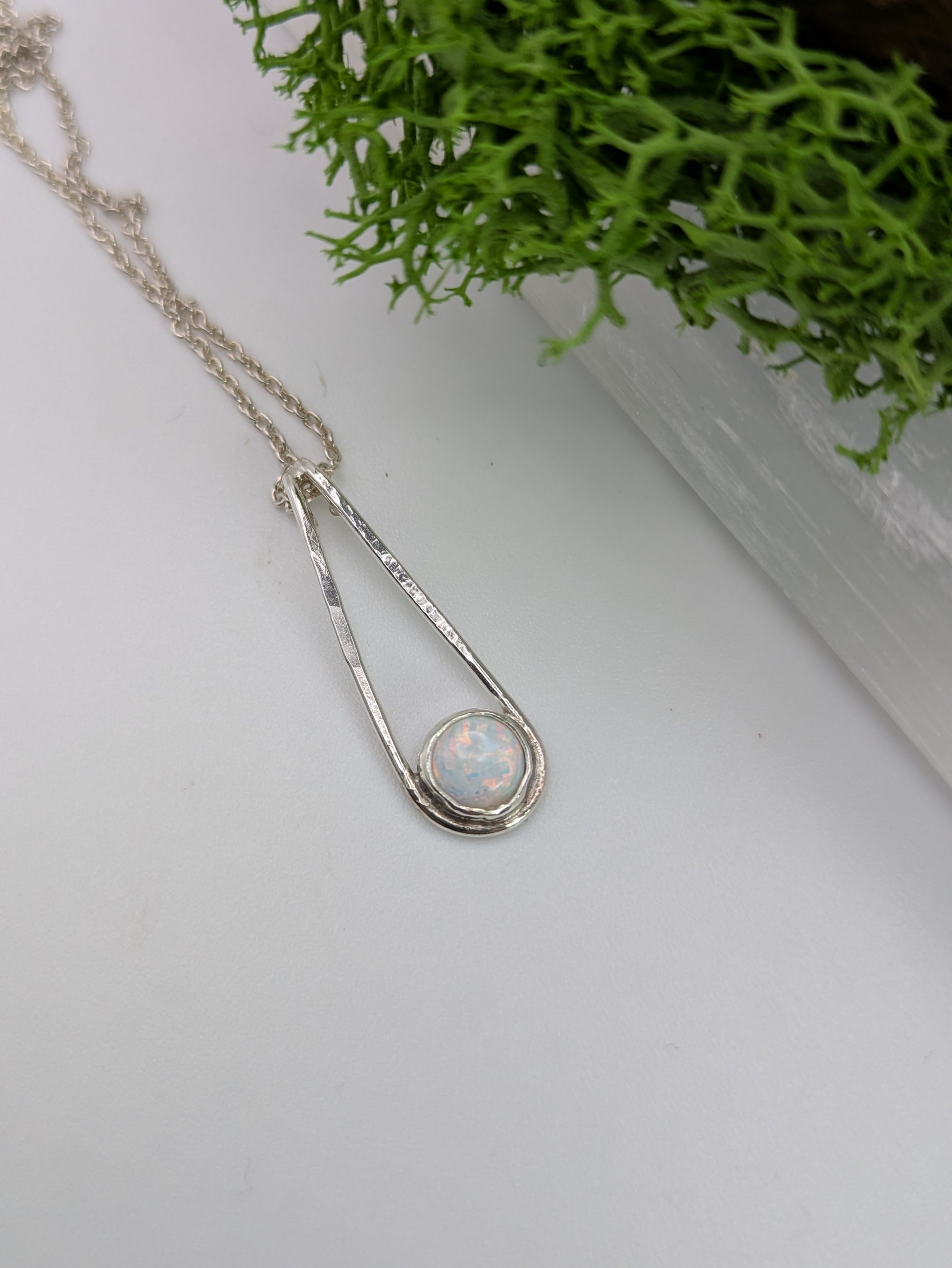 Sterling silver pendant in a Teardrop shape with a glowing Kyocera opal in soft pink and blue tones, fully hallmarked and displayed on a neutral background.