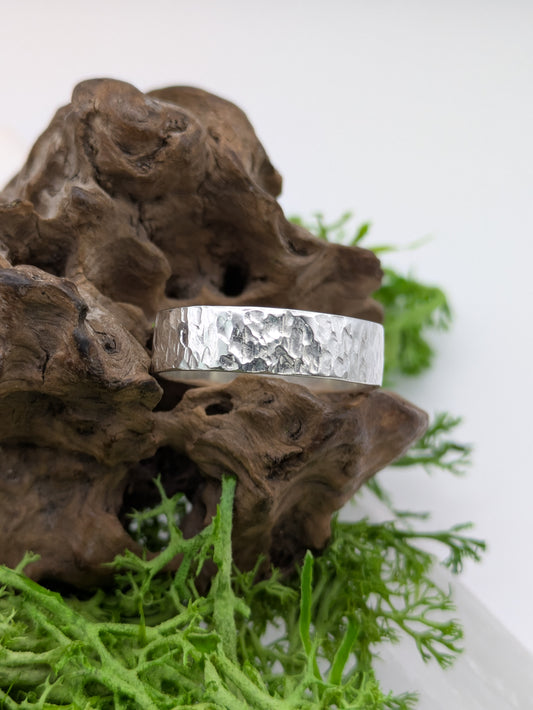Textured Silver ring on a piece of driftwood with greenery