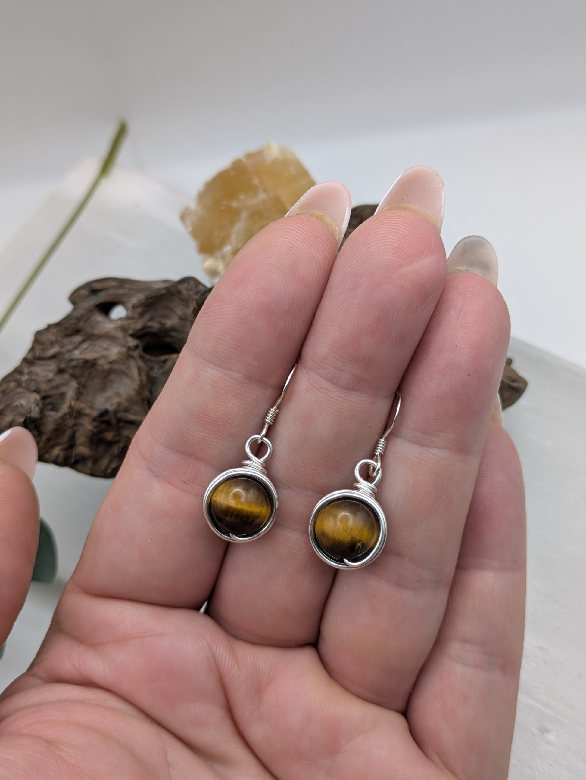 Silver earrings featuring round Tiger’s Eye gemstones with golden-brown chatoyancy.