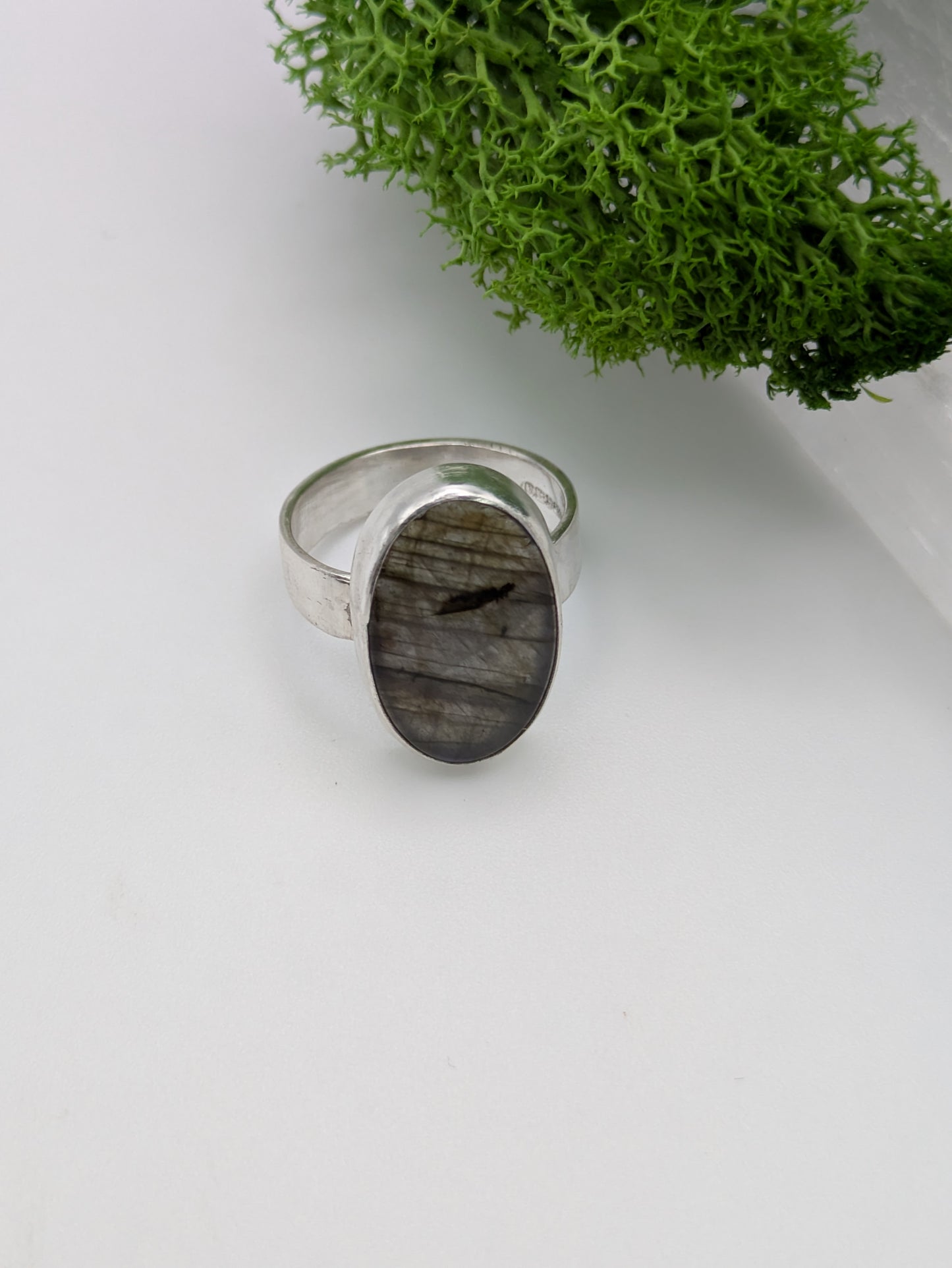 Sterling silver ring featuring a luminous purple labradorite with violet and silver flashes, fully hallmarked and photographed on a soft neutral background.