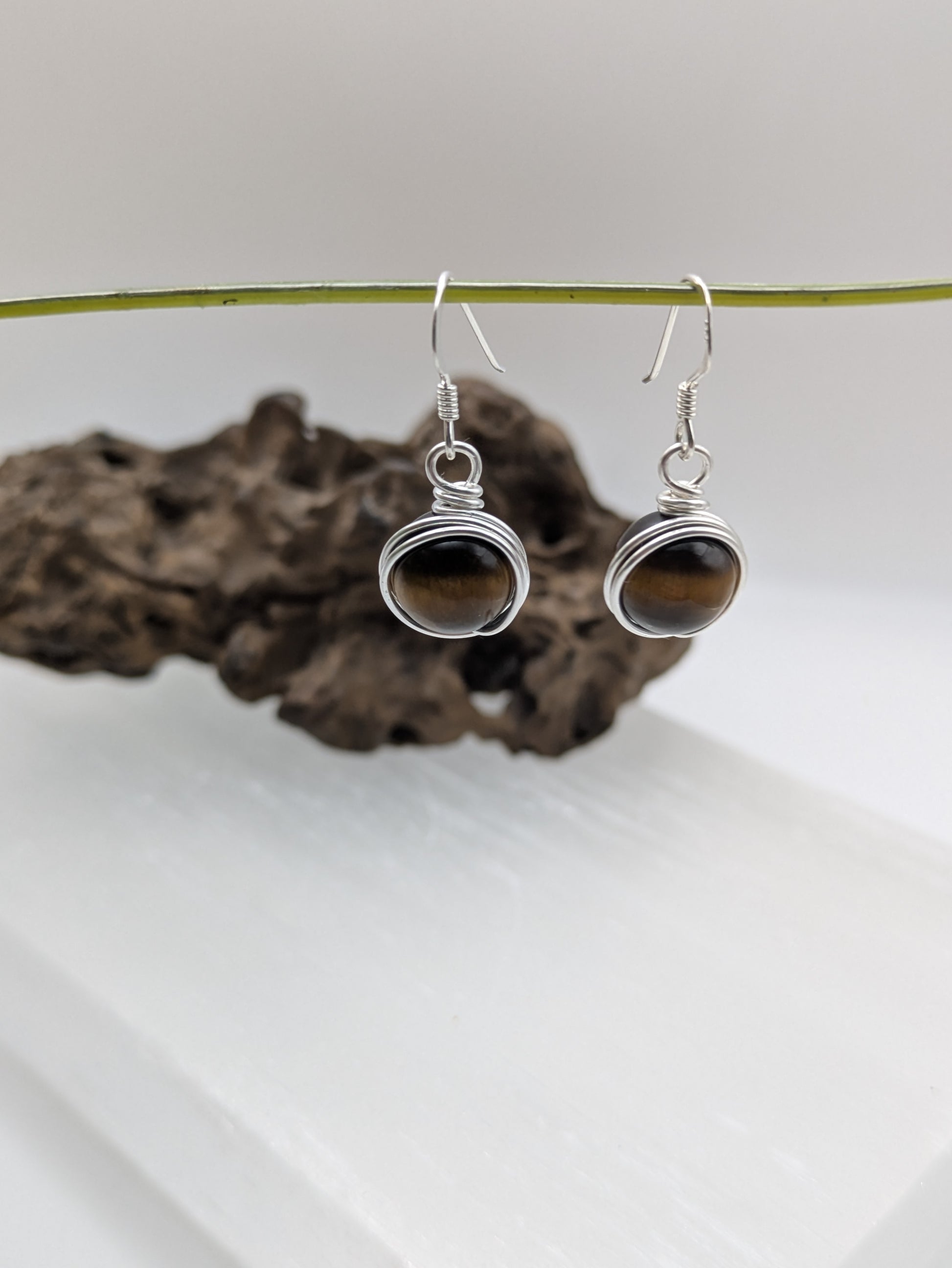 Silver earrings featuring round Tiger’s Eye gemstones with golden-brown chatoyancy.