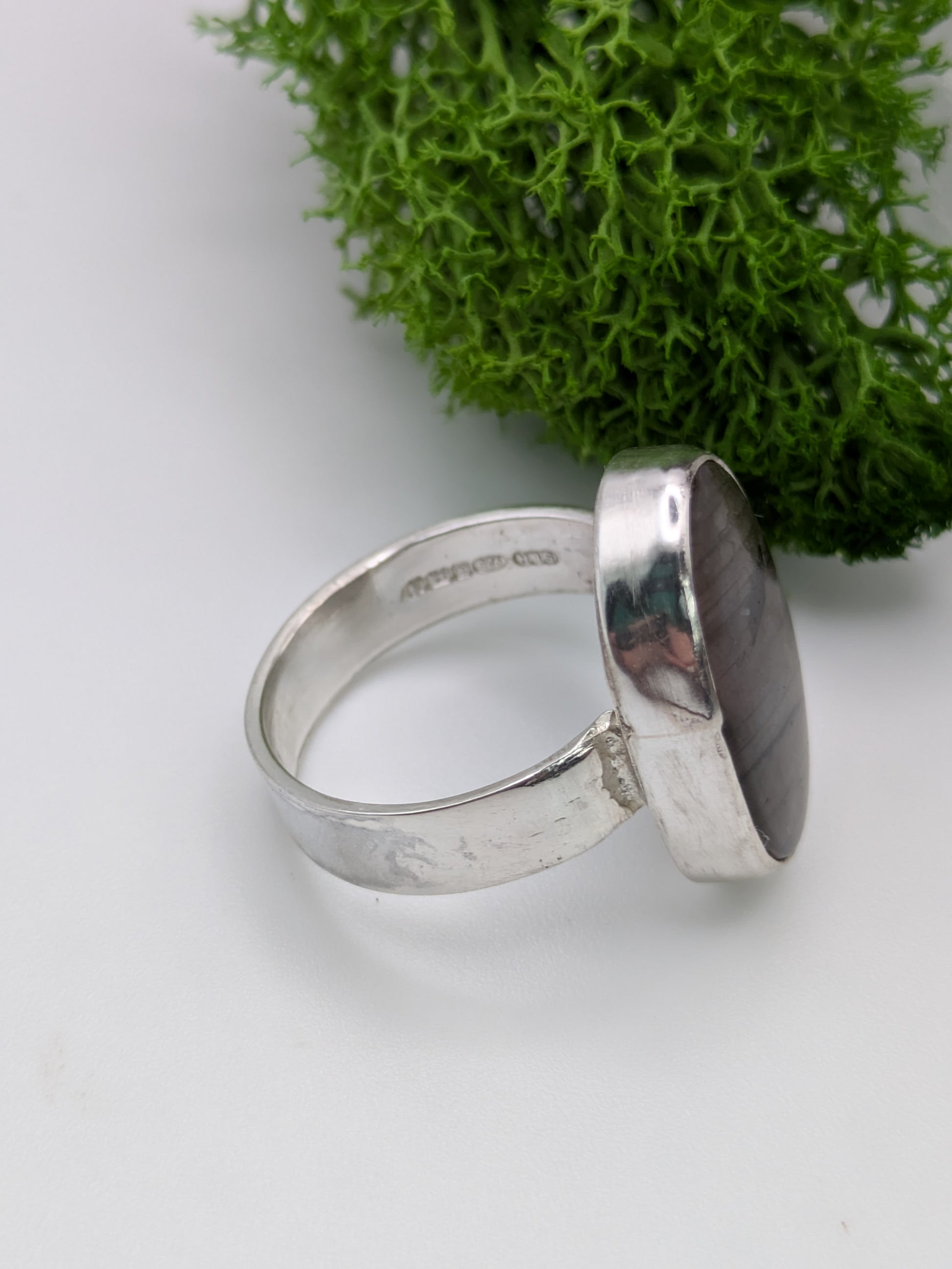Sterling silver ring featuring a luminous purple labradorite with violet and silver flashes, fully hallmarked and photographed on a soft neutral background.