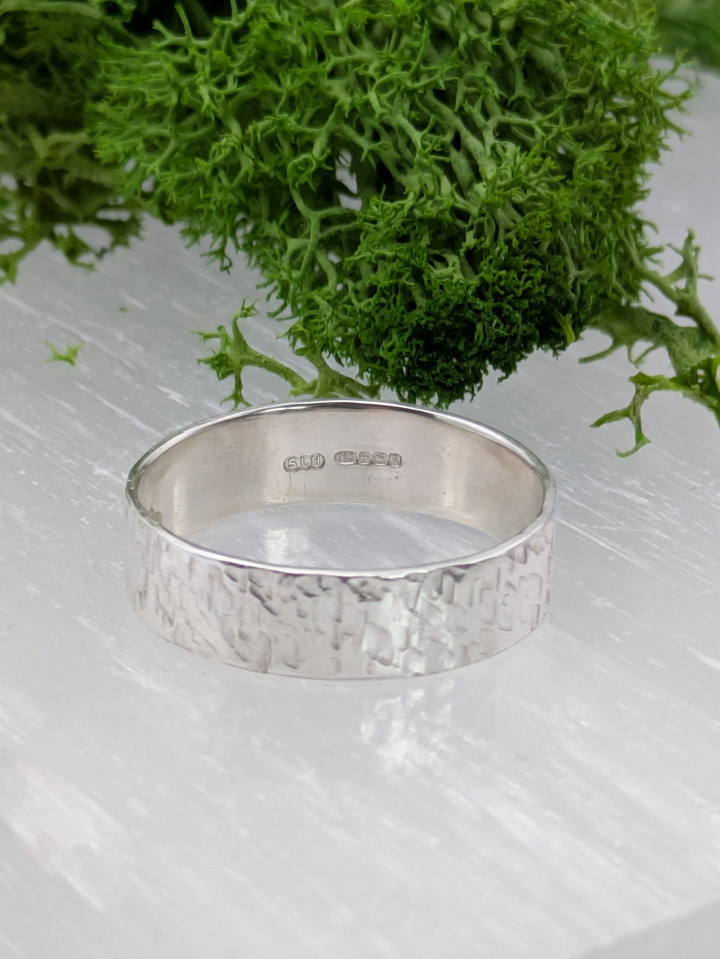 Fully hallmarked Textured Sterling Silver ring on a piece of driftwood with greenery
