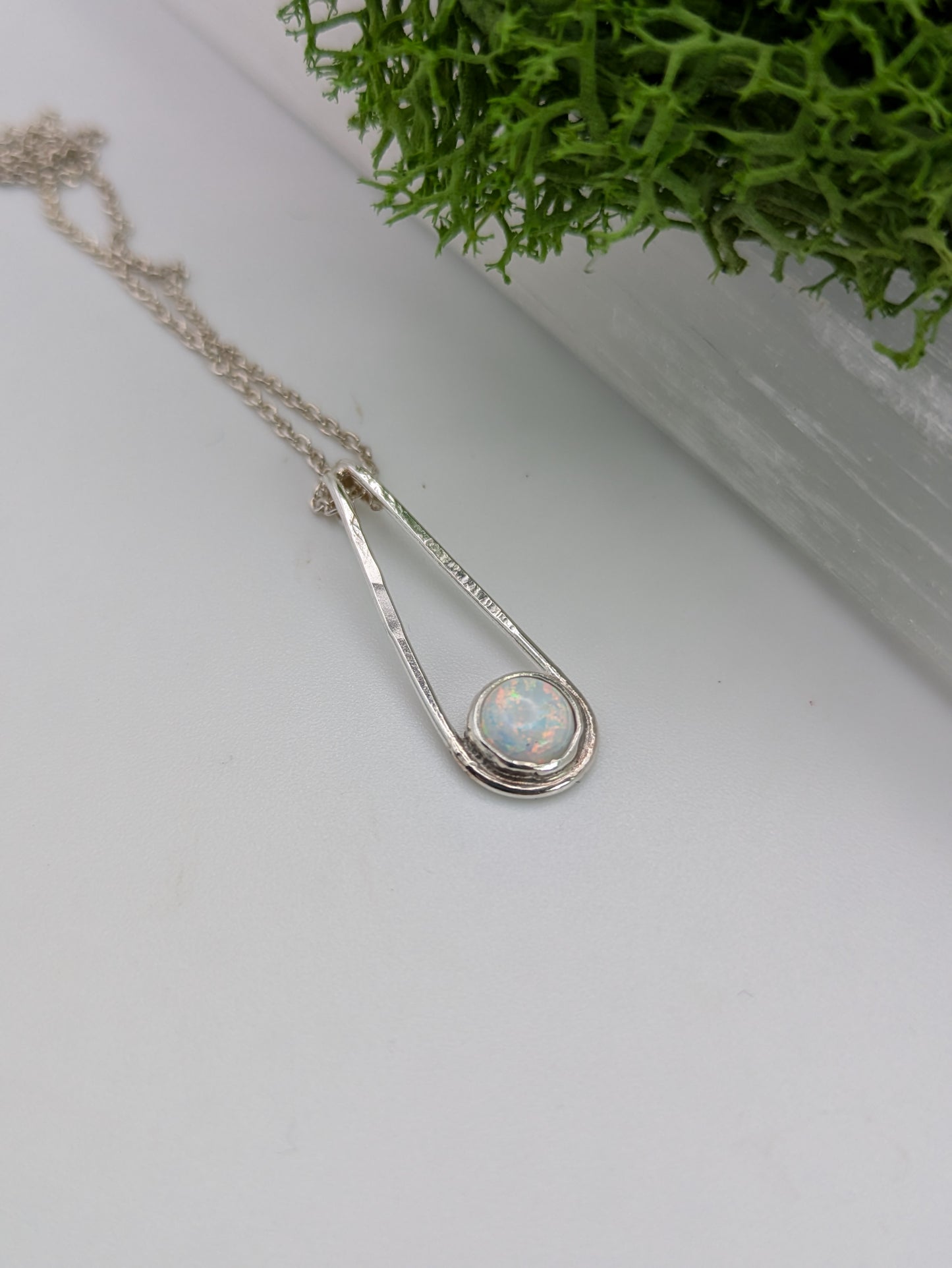 Sterling silver pendant in a Teardrop shape with a glowing Kyocera opal in soft pink and blue tones, fully hallmarked and displayed on a neutral background.