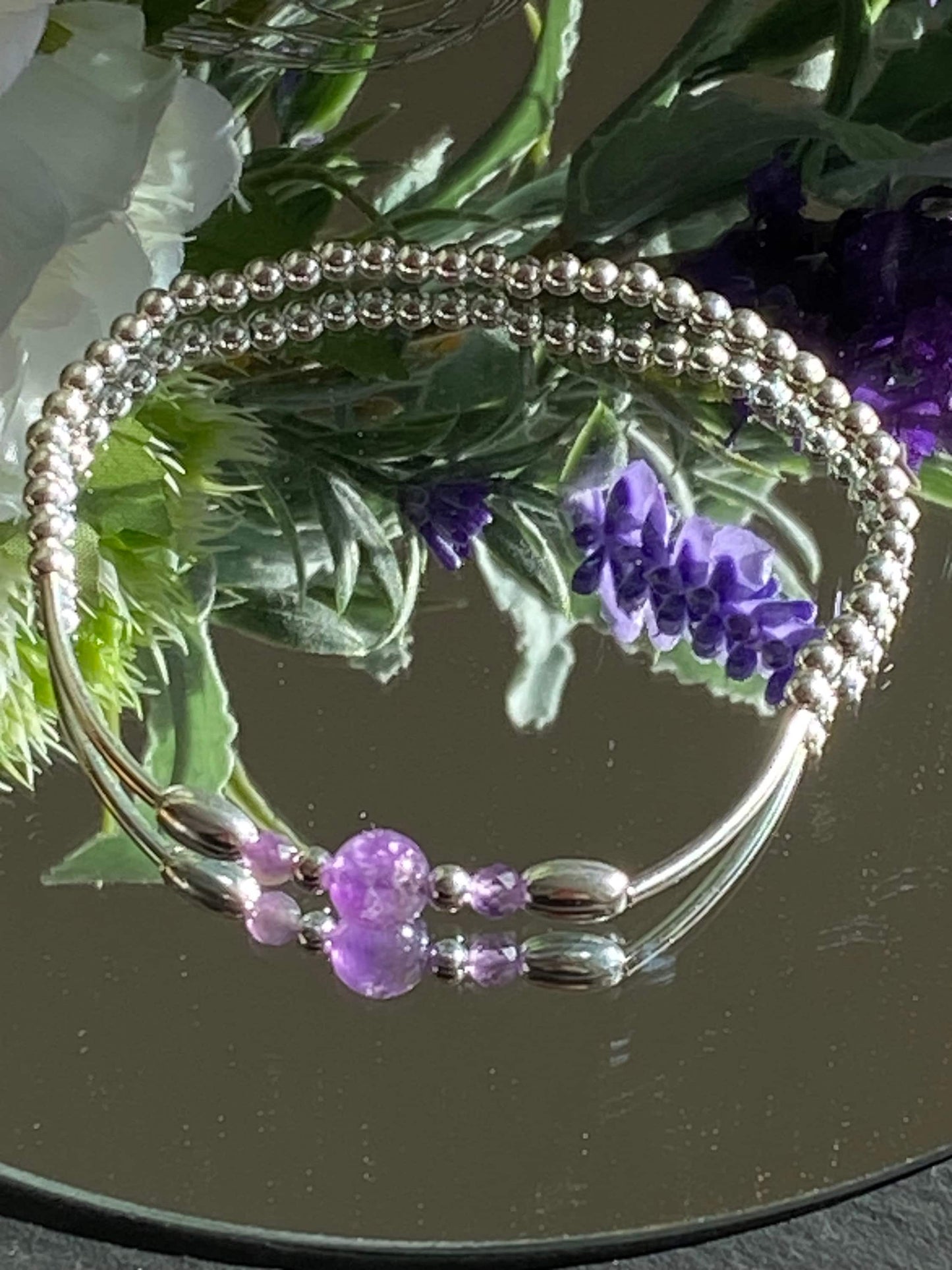 <img src="amethyst-bracelet.jpg" alt="Handmade amethyst bracelet with sterling silver beads, a calming purple crystal design for February birthdays and spiritual protection">